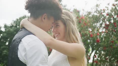 Happy-diverse-couple-in-garden-on-sunny-day-at-wedding