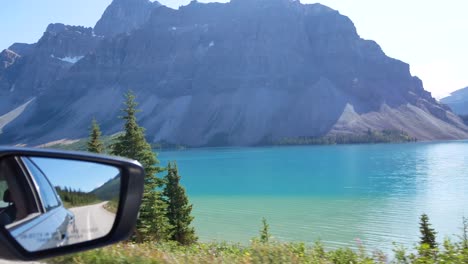 pov of side mirror of car while driving pass bow lake and rockies mountain range in banff national park,alberta,canada in summer holiday time