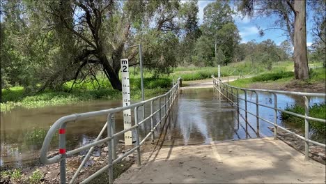 toma deslizante suave de izquierda a derecha de un puente peatonal inundado sobre un arroyo crecido después de la lluvia torrencial y la inundación en las inundaciones australianas en octubre de 2022