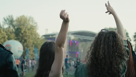 rear view of friends dancing on music festival with hands up.