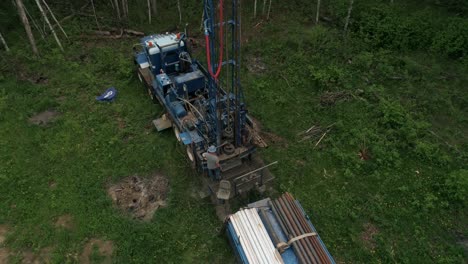 overhead panning aerial view of water well drilling rig operator adding an additional length of pipe