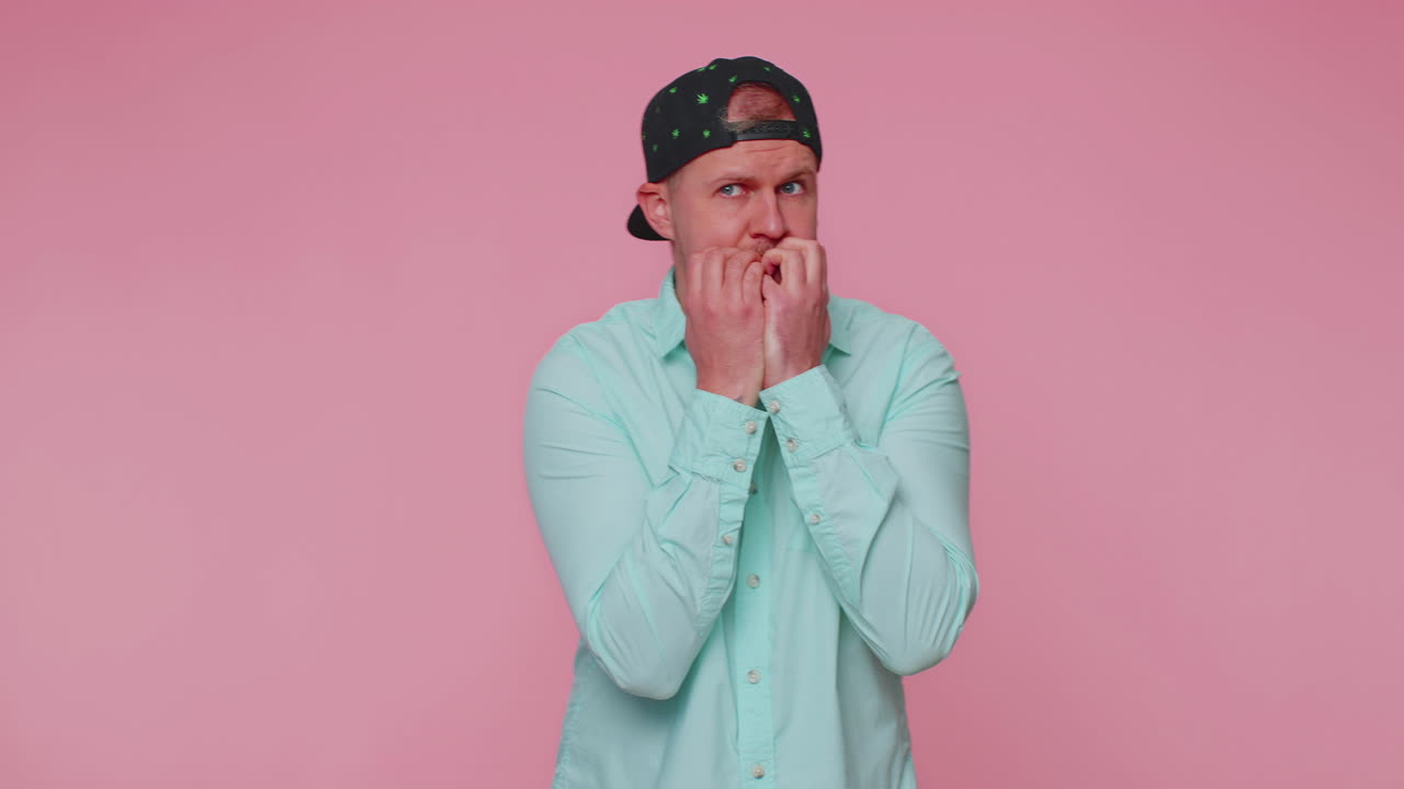 Young scared man biting nails, feeling worried nervous about serious troubles, stress and anxiety