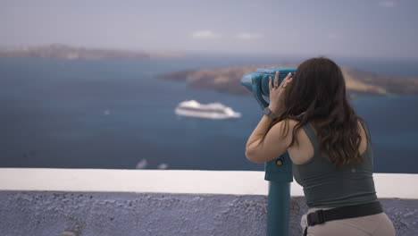 Slow motion shot of a tourist looking through binoculars viewing Santorini