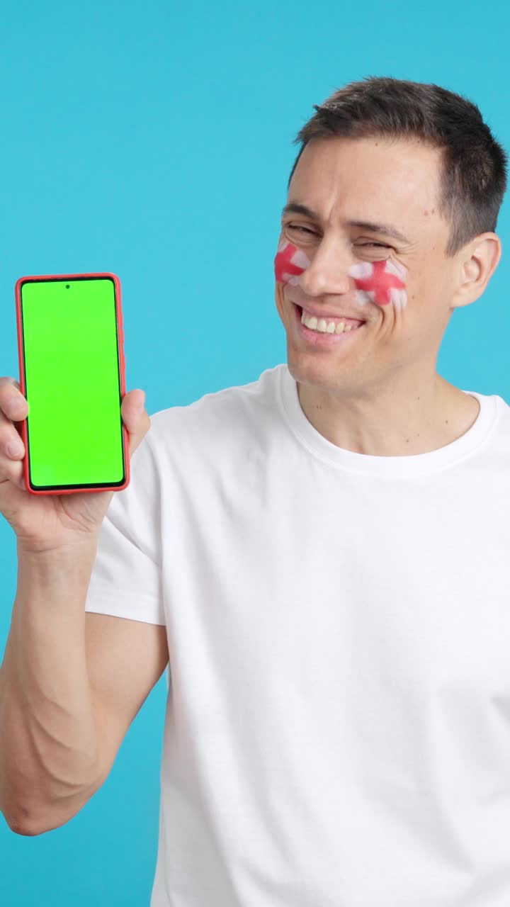 English man looking at his mobile smiling and showing it