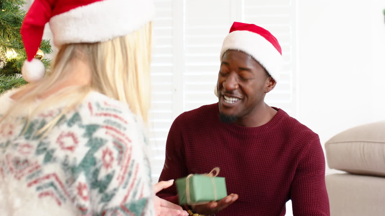 Smiling man in Santa hat holding gift, sharing joyful moment at Christmas