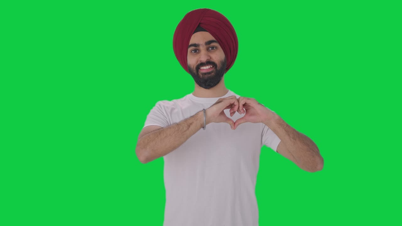 hombre indio sikh feliz mostrando el signo del corazón pantalla verde