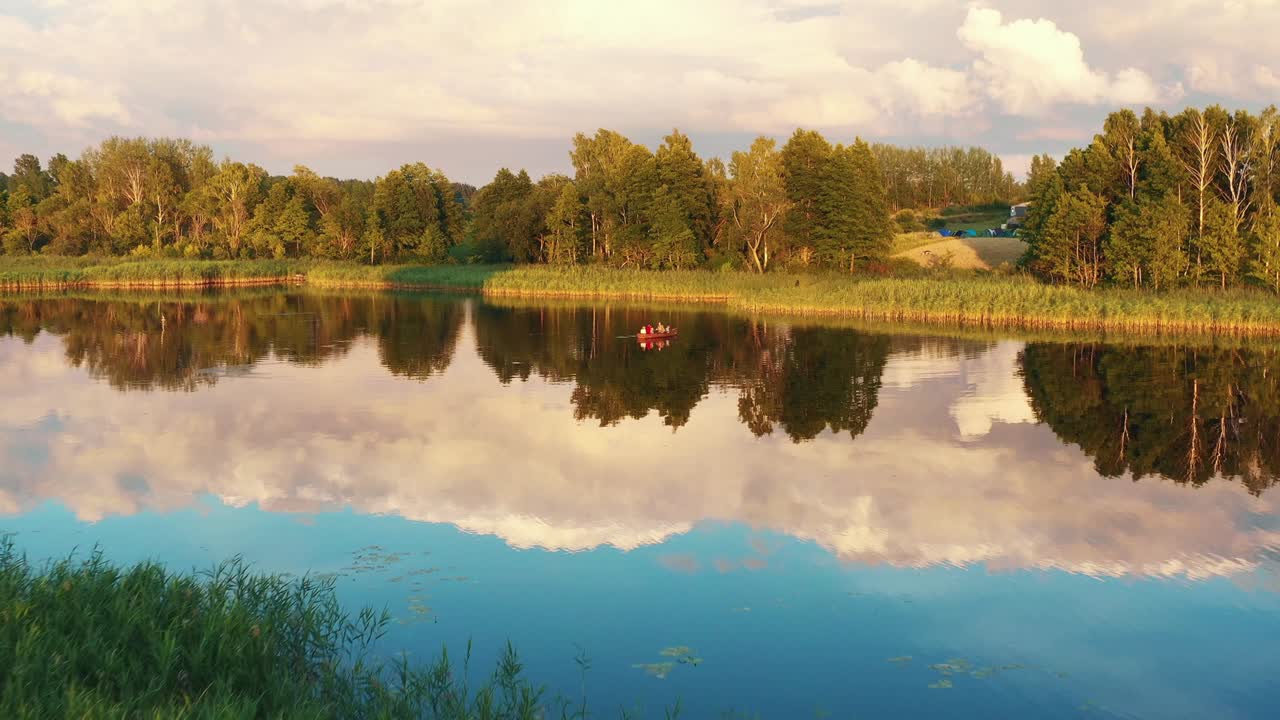 дрон летит к счастливой семье с детьми, наслаждающимися прогулкой на лодке на невероятном летнем восходе солнца на тихом озере.