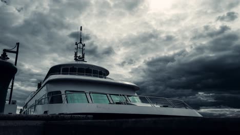 thunderstorm and dramatic clouds over the lake memphremagog with a tourist boat anchored in wharf in magog, quebec, canada