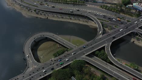 aerial panning shot above complex road system connecting bridges on and off ramps and loops over canal and river in ho chi minh city, vietnam on a sunny day