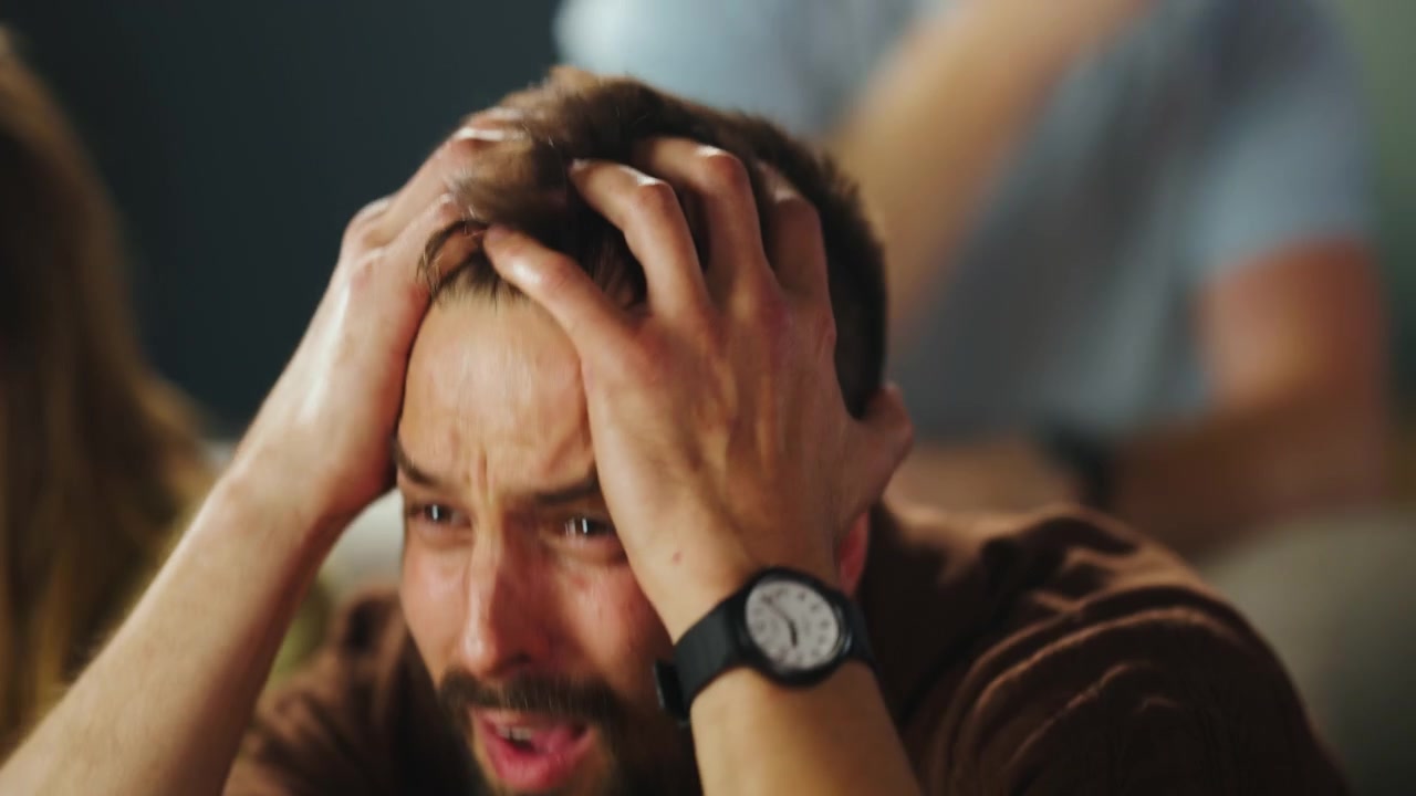 Uomo stressato che guarda una partita sportiva con amici a casa