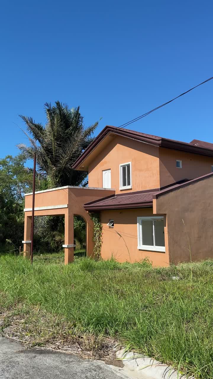Perspectiva ao nível do solo mostrando uma fila de casas com tinta rachada e acabamentos exteriores envelhecidos, com equipamentos de construção antigos