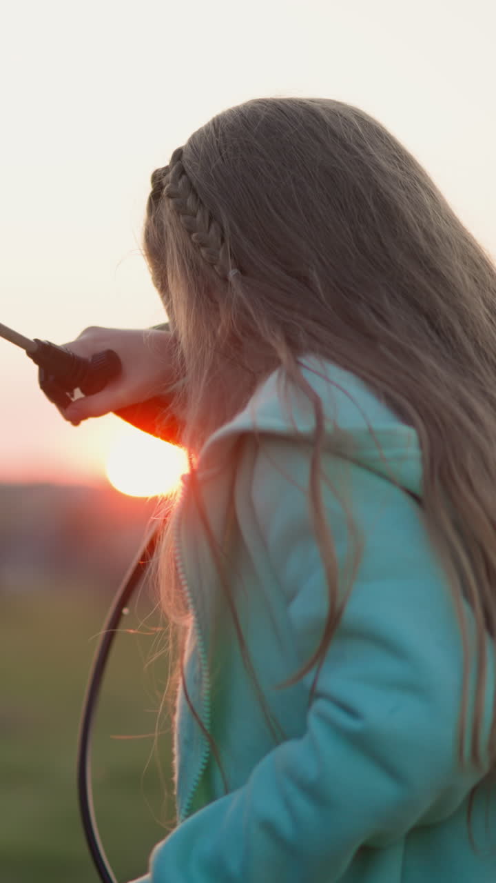 niño feliz lava el coche en el prado al atardecer. niña rubia con toallitas de rociador cae de la cara en el césped al anochecer. niño aprende a hacer las tareas