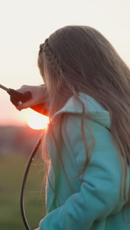 niño feliz lava el coche en el prado al atardecer. niña rubia con toallitas de rociador cae de la cara en el césped al anochecer. niño aprende a hacer las tareas
