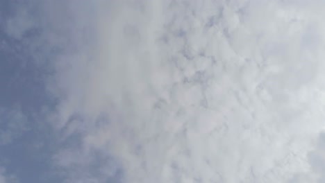 Light-wispy-hazy-high-cirrus-stratus-clouds-floating-past-a-powder-blue-background-sky,-aerial