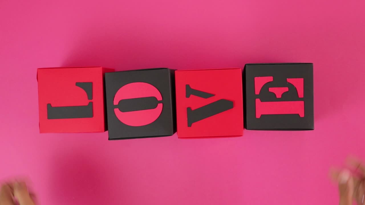 Arranging handmade paper cubes with glued letters forming word LOVE