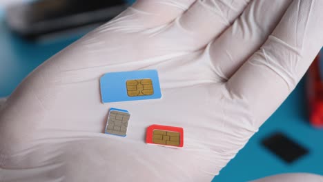 hand in white gloves hold different types and sizes of sim cards