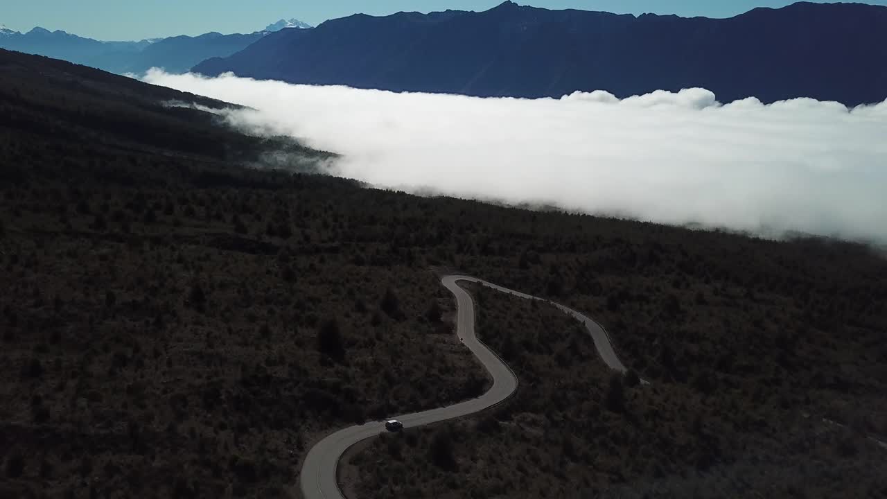 Aerial View of Lonely Car on Curvy Road in Volcanic Region of Chile With Stunning View of Clouds in the Valley
