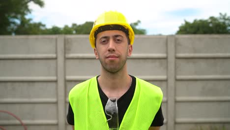 a construction worker wearing a yellow hard hat positioned his standard safety spectacles on the neckline of his shirt - medium close up