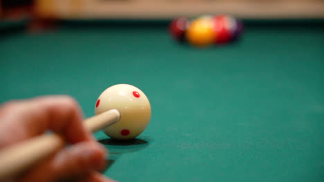 slow motion billiards low angle close up of cue ball as person breaks a rack of 9 ball on a pool table with green felt and the cue stick bending as balls are contacted and skatter, closed bridge