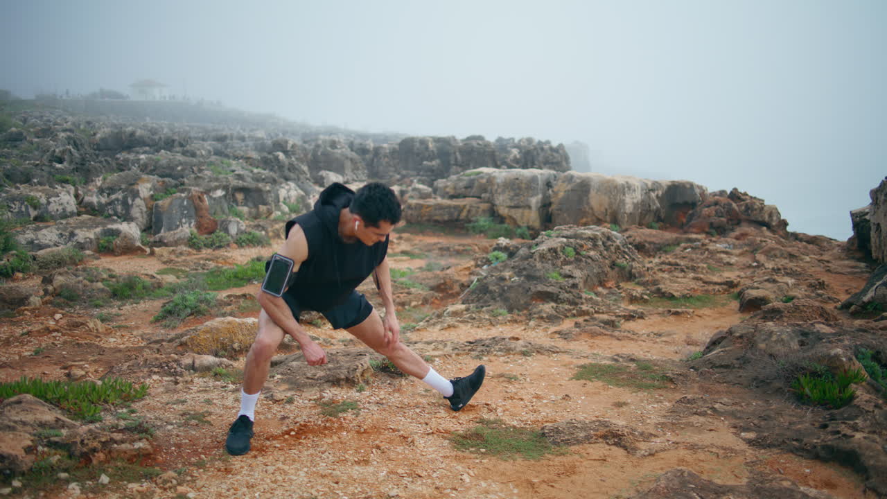 atleta profesional practicando al aire libre en la orilla del mar. corredor enfocado estira las piernas