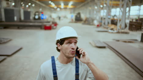 maintenance technician standing in industrial factory, talking on mobile phone