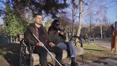 blind man sitting on park bench chatting with his wife.