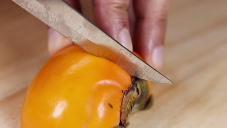 a persimmon being sliced with a knife