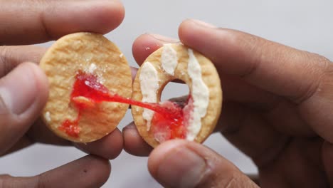 persona sosteniendo una galleta de sándwich con relleno de mermelada