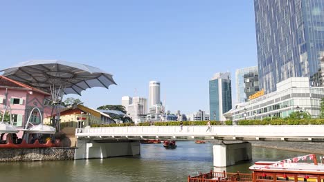 a riverboat glides past clarke quay’s colorful buildings and modern skyscrapers in bright daylight, captured with smooth lateral camera movement