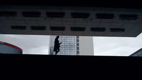 silhouette female person walking in dark building at city downtown.