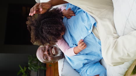 vertical video of grandchildren surprising grandfather resting on seat in garden at home