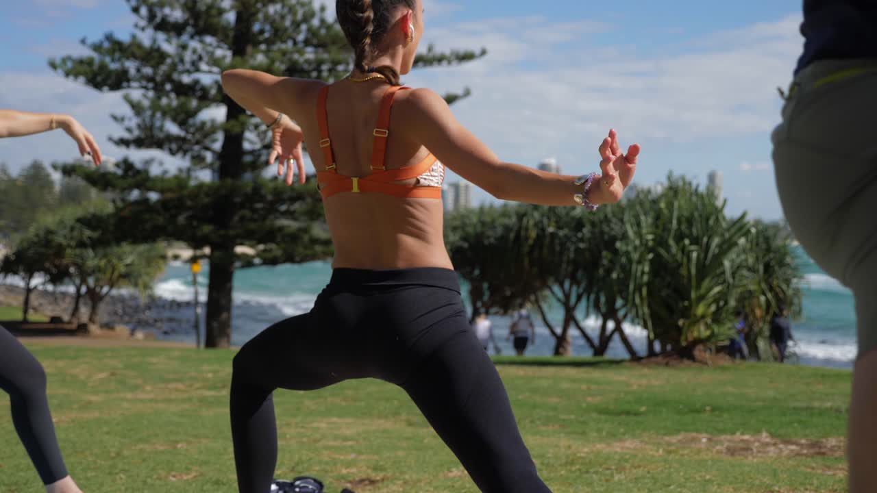 Piger i sportstøj, der dyrker yoga og laver udvidet sidevinkel – Burleigh Hill og Burleigh Heads Strand – Gold Coast, QLD, Australien