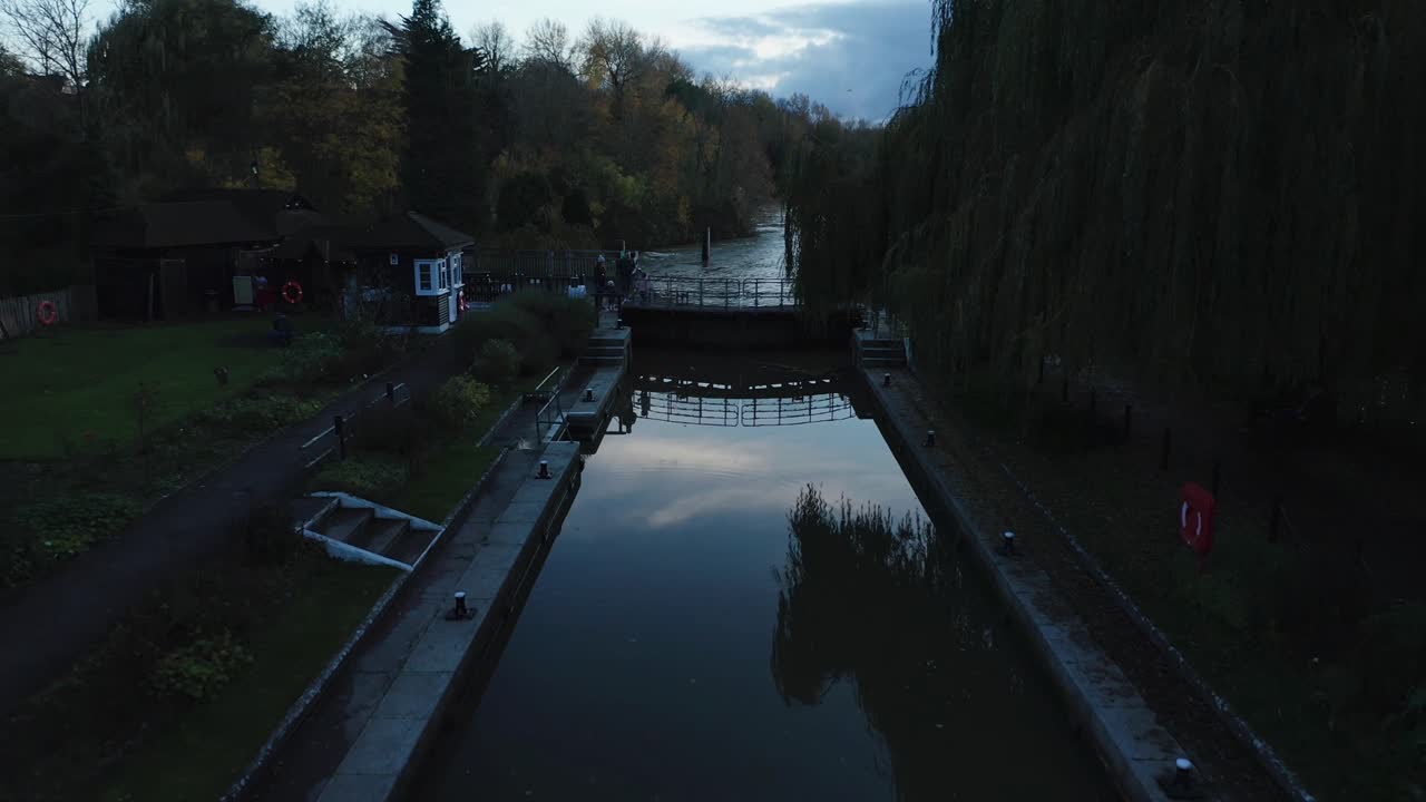 Oxford's Isis River with canal, traditional houses, and people walking and enjoying nature.