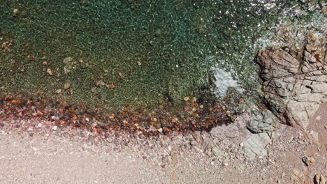 Small-Waves-Breaking-On-Pebbles-Beach-During-Summer-In-Sardinia,-Italy---aerial,-top-down