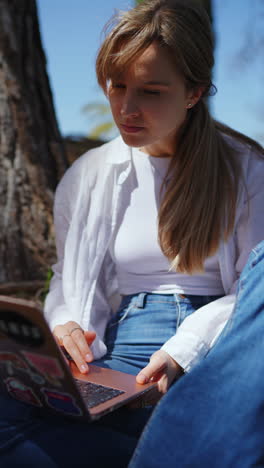 mujer joven trabajando en una computadora portátil en un parque