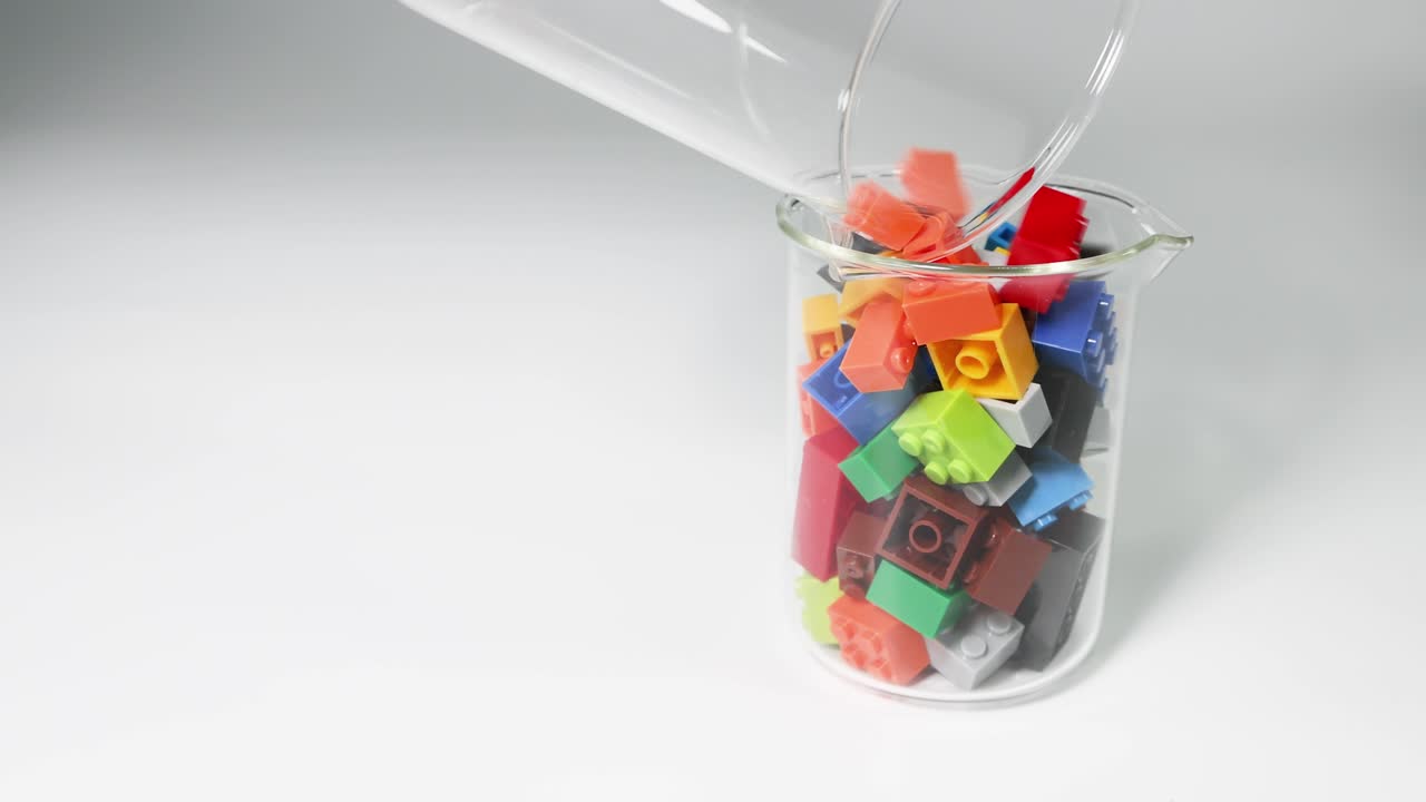 manos transfiriendo bloques coloridos en un vaso transparente