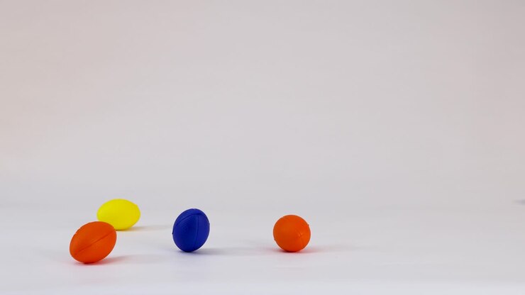 Flerfarvede stressbolde af skum formet som fodbolde hopper og ruller hen over en hvid overflade