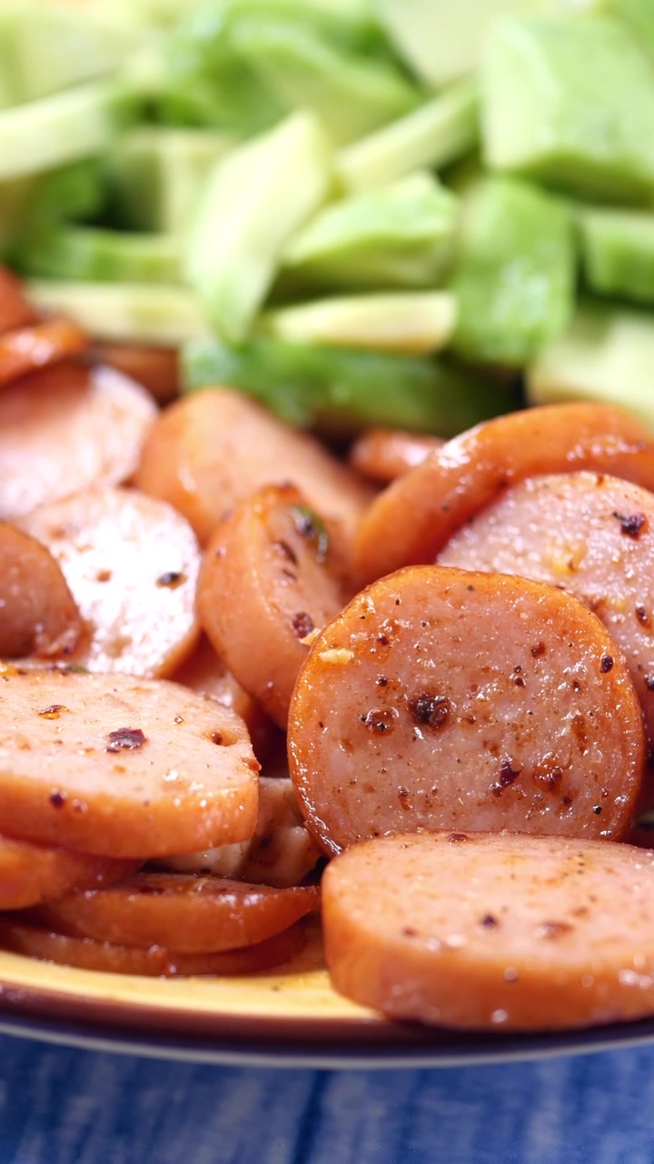 Primo piano di salsiccia a fette cotta con verdure verdi