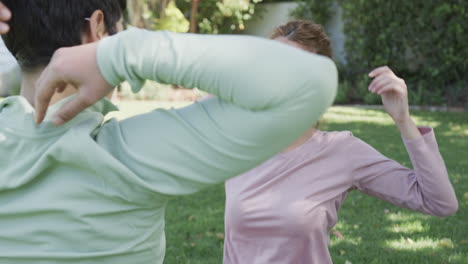 happy caucasian lesbian couple stretching in sunny garden, slow motion