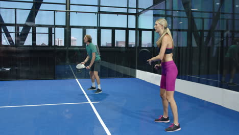 women playing padel tennis on indoor court, focusing on competitive match