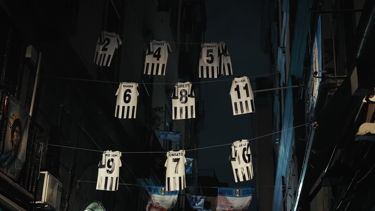 Esposizione di maglie da calcio in un vicolo a Napoli, Italia, di notte
