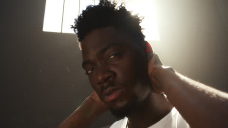 reflective black inmate holding his head under sunlight from prison window
