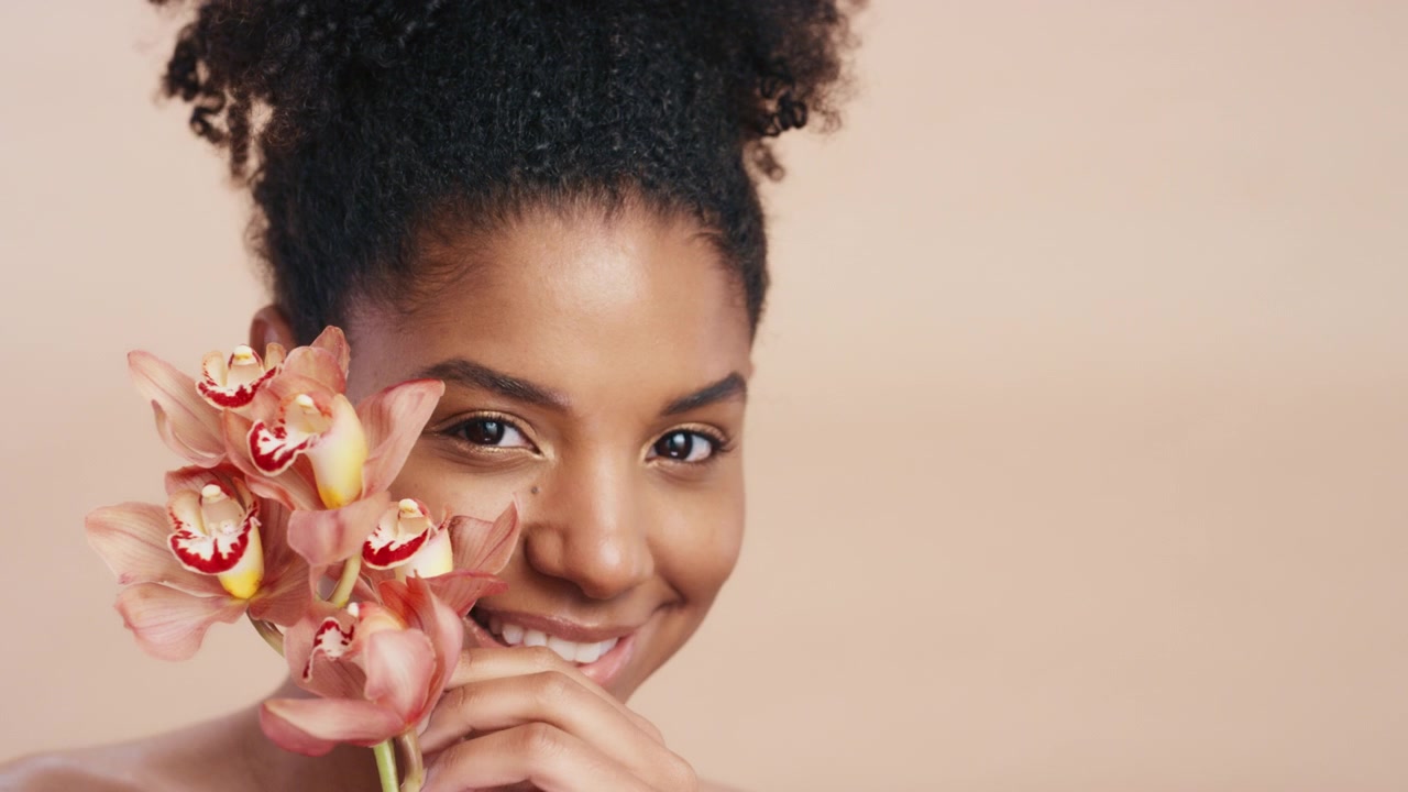 Giovane donna con un fiore di orchidea vicino al viso
