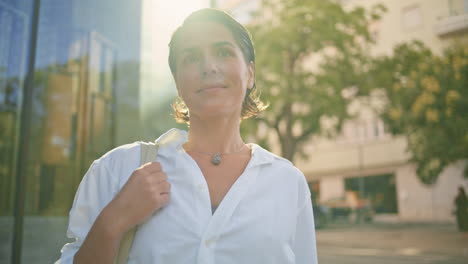 mujer de negocios feliz mirando cámara sol retrato del centro de la ciudad. mujer posando ciudad
