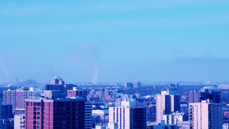 Edificios-De-Apartamentos-De-Baja-Altura-De-Lapso-De-Tiempo-De-4k-Con-Vapor-Saliendo-De-Los-Calentadores-En-Una-Tarde-De-Invierno-Soleada-Y-Ventosa-En-Primer-Plano-Y-Estructuras-De-Fábrica-En-El-Fondo-Bombeando-Humo-Blanco-Y-Espeso