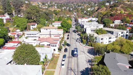 Aerial-Tilt-Up-Reveal-Beachwood-Drive-In-Hollywood-With-Bus-Driving-Up-Towards-Hollywood-Sign