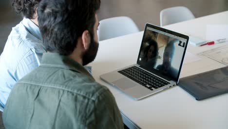 vista posterior de dos hombres haciendo una llamada de video a través de una computadora portátil