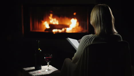 an evening with a book and a glass of wine by the fireplace woman reads in the living room