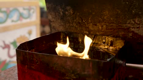 4k, lighting a fire in an oil furnace to wait for tourists to bring incense and candles to burn at a chinese shrine to pray to the gods