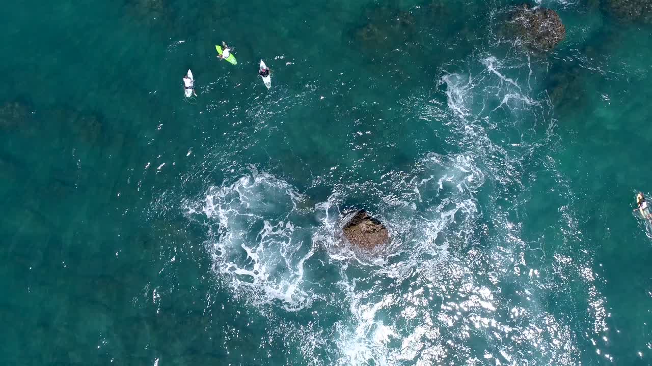 amplia toma de arriba hacia abajo desde la vista aérea de los surfistas esperando una ola cerca de la roca